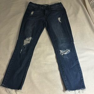 Dark colored blue jeans wire couple times with holes